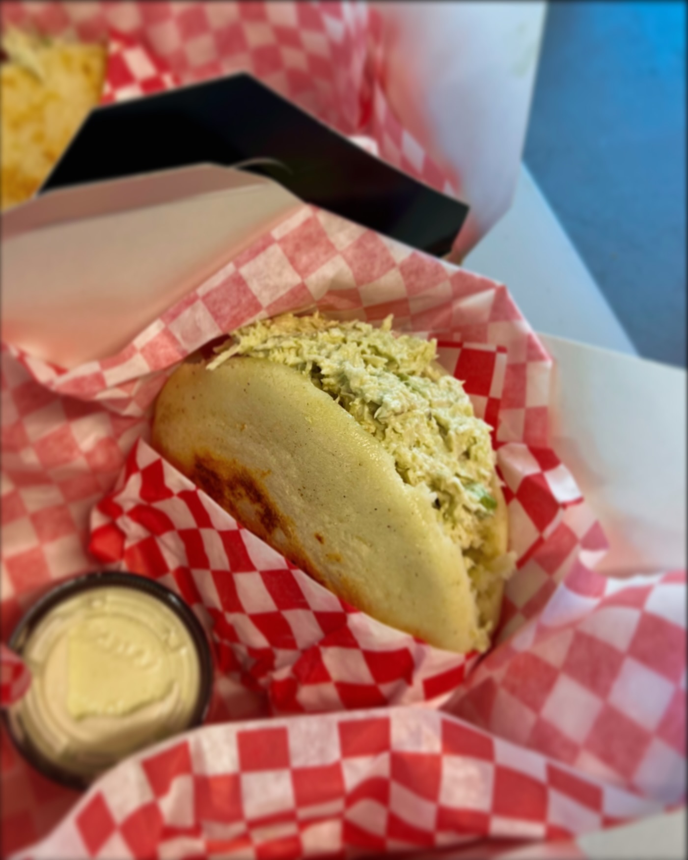 An arepa with creamy chicken filling and a dipping sauce