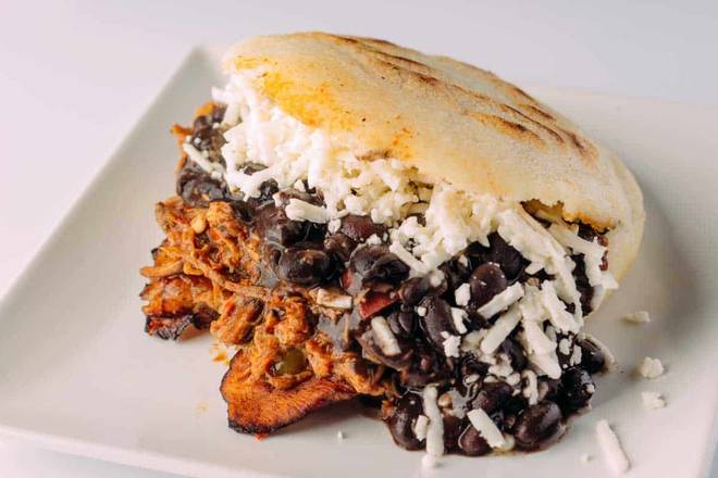 An arepa filled with shredded meat, black beans, and white cheese