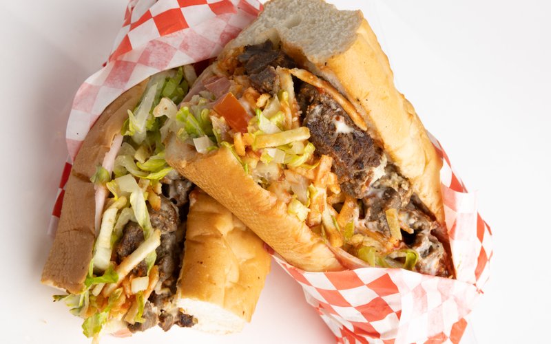 A loaded pepito sandwich with meat and shredded cheese