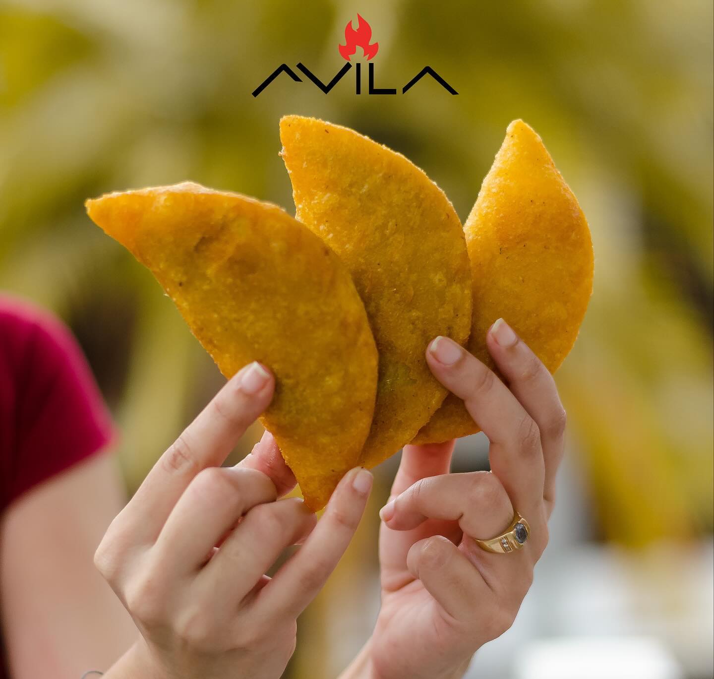 Hands holding three golden empanadas