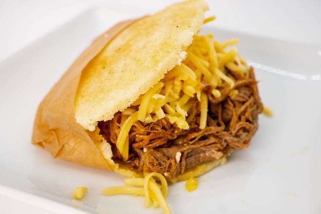 An arepa filled with shredded beef and yellow cheese