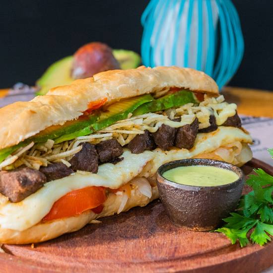 A large mixed-meat pepito with tomato, lettuce, cheese, and sauce