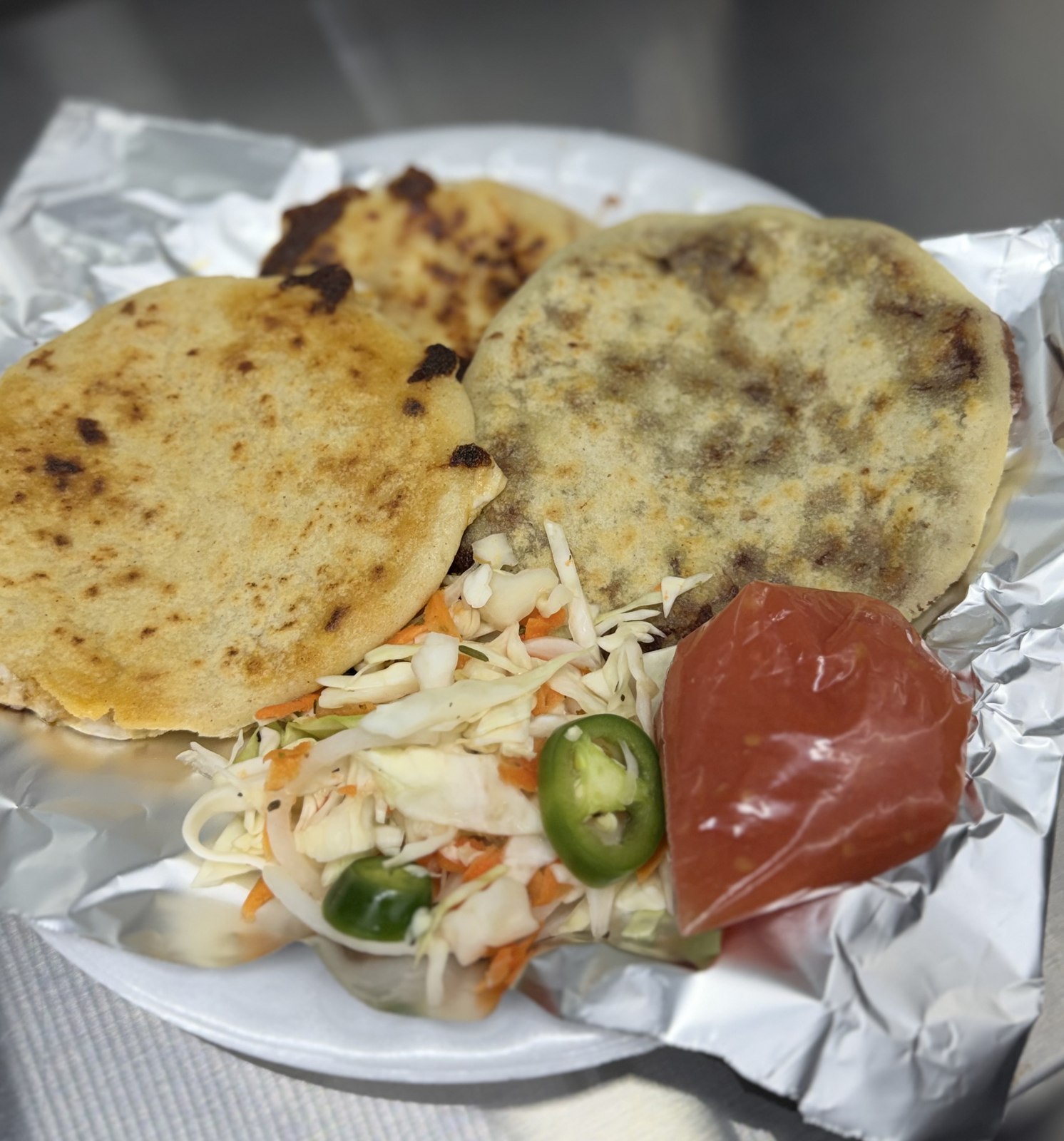 Two handmade pupusas with curtido slaw, jalapeño, and salsa