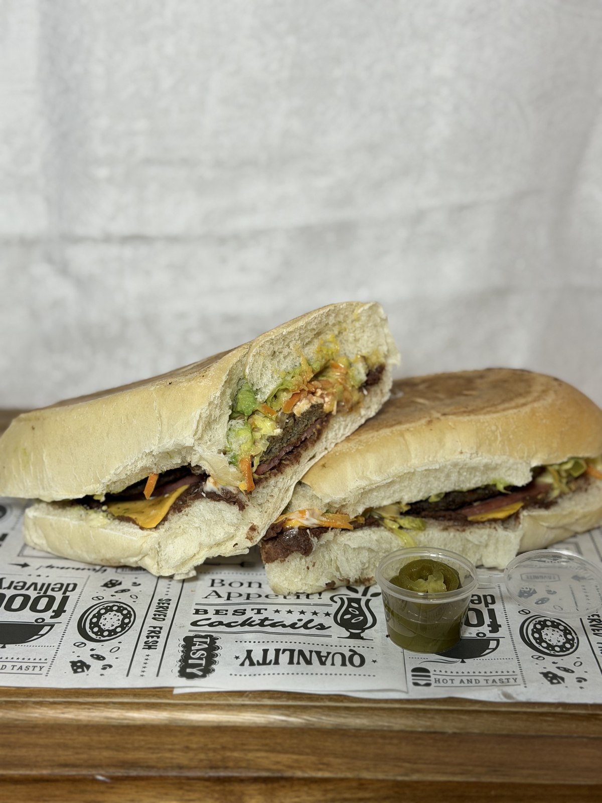 A Torta Hula Hula sandwich sliced in half showing steak, cheese, and slaw