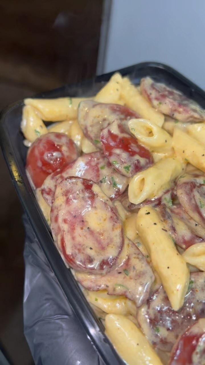 Creamy penne pasta with sliced sausage and herbs