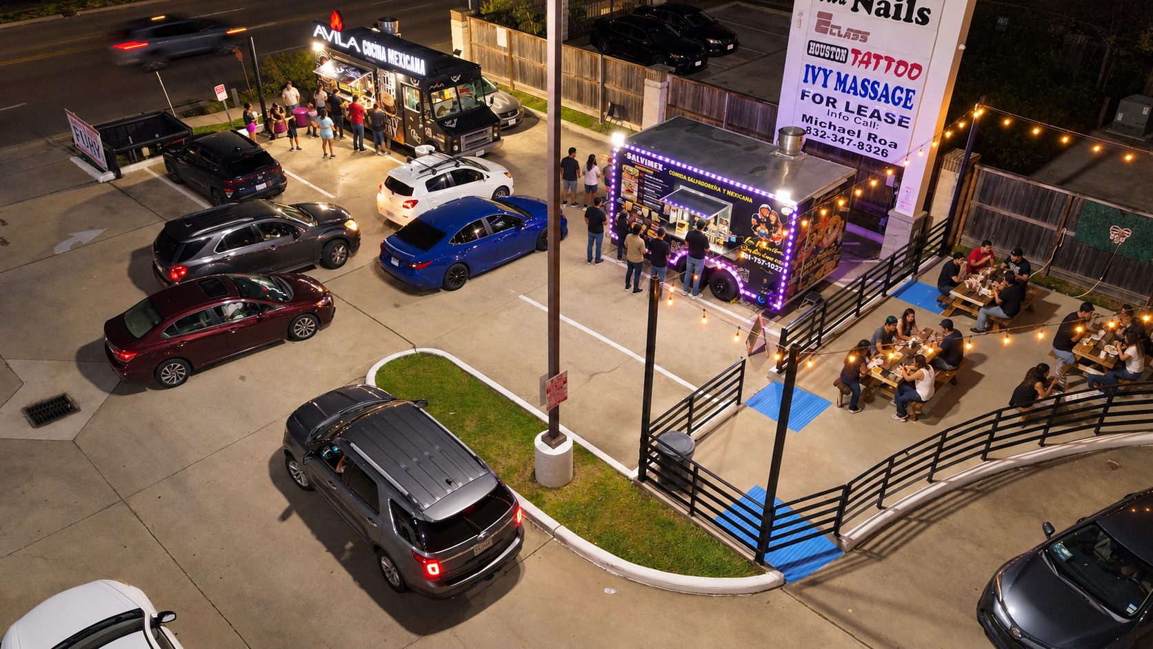 Overhead view of Truck Stop 77077 at night with Avila and La Familia Salvimex serving and full picnic tables
